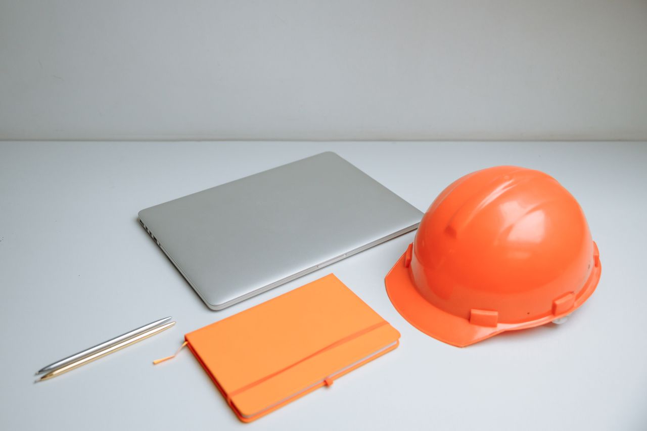 Mastering the First Impression: Your intriguing post title goes here Sleek desk setup featuring a laptop, notebook, and orange hardhat.